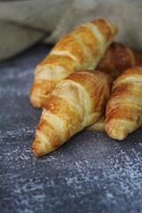 Croissant bread stacked on the table with wooden plates and sackcloth.