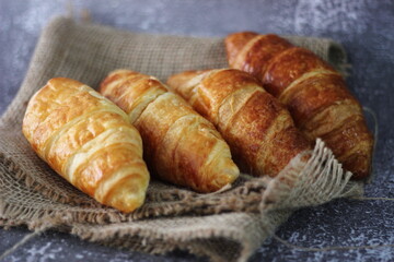 Croissant bread stacked on the table with wooden plates and sackcloth.