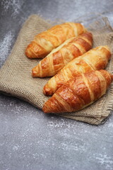 Croissant bread stacked on the table with wooden plates and sackcloth.