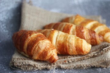 Croissant bread stacked on the table with wooden plates and sackcloth.