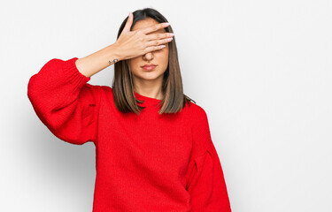 Beautiful brunette woman wearing casual winter sweater covering eyes with hand, looking serious and sad. sightless, hiding and rejection concept
