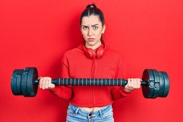 Beautiful woman with blue eyes wearing sportswear using dumbbells skeptic and nervous, frowning upset because of problem. negative person.