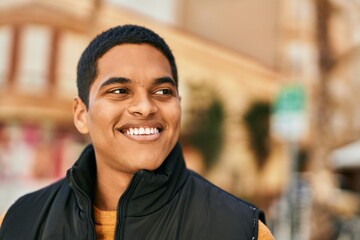 Young latin man smiling happy standing at the city