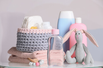 Baby cosmetic products, toys and accessories on white table against color background