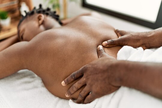 African american woman reciving back massage at the clinic.