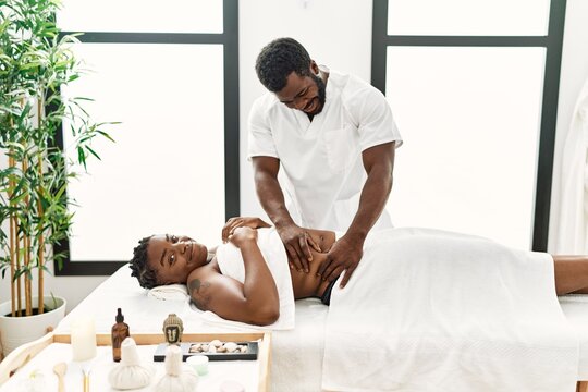 Young physiotherapist man giving abdominal massage to african american woman at the clinic