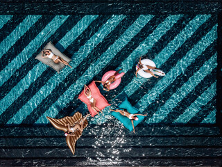 Top view of sexual lovely women floating in the pool on inflatable mattresses of different interesting shapes. Summer holiday concept