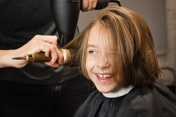 Hair styling in beauty salon after bob haircut. Hairdresser hold hairdryer and comb to style hair....