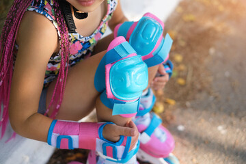 A child in protective sports equipment from bruises during falls sits and rests after roller...