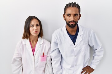 Young hispanic doctors standing over white background skeptic and nervous, frowning upset because of problem. negative person.