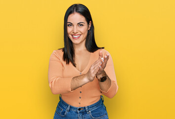 Young hispanic woman wearing casual clothes clapping and applauding happy and joyful, smiling proud hands together