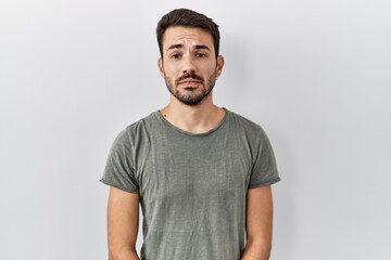 Obraz premium Young hispanic man with beard wearing casual t shirt over white background depressed and worry for distress, crying angry and afraid. sad expression.