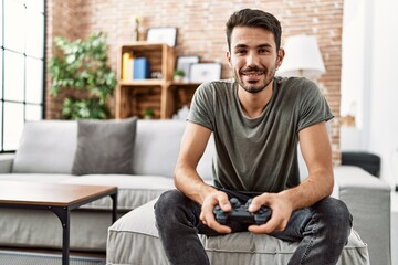 Young hispanic man smiling confident playing video game at home © Krakenimages.com