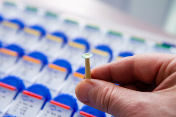 A male optician doctor shows a new clear and clean contact lens leaning on a stick support. In the...