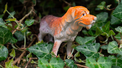 Toy dog figurine surrounded by green leaves.