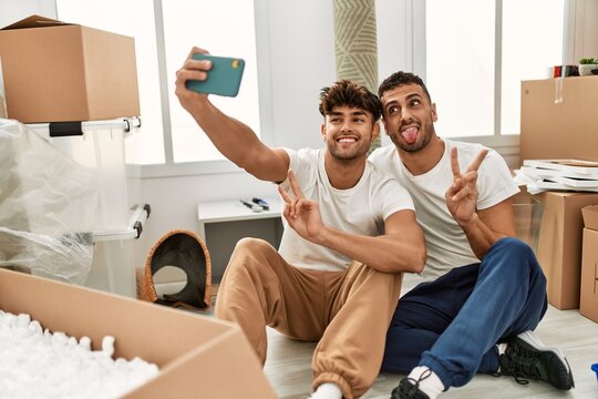 Two hispanic men couple smiling confident make selfie by the smartphone at new home