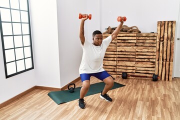 Fototapeta na wymiar Young african man training with dumbbells at the gym