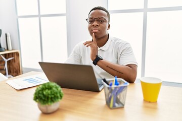 Young african man working at the office using computer laptop thinking concentrated about doubt...