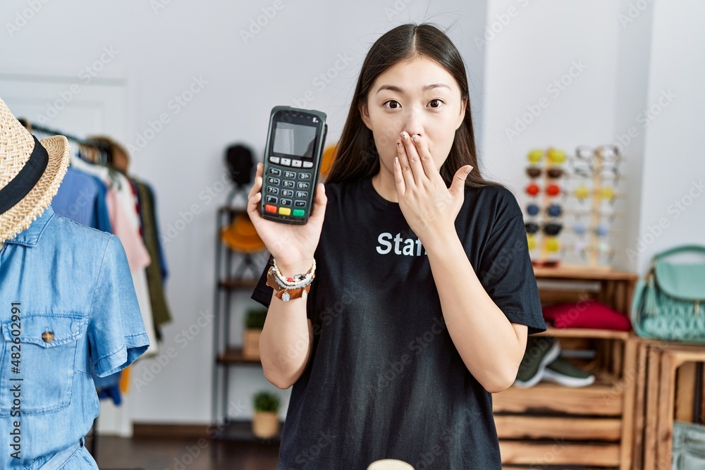 Sticker young asian woman working as manager at retail boutique holding dataphone covering mouth with hand, 