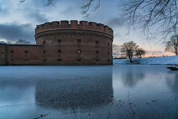 Old brick tower surrounded by a frozen moat
