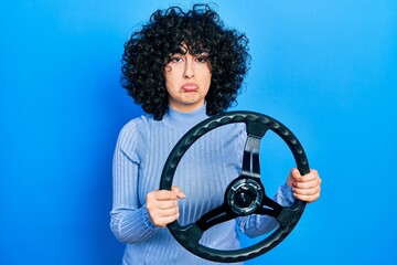 Young middle east woman holding steering wheel depressed and worry for distress, crying angry and...