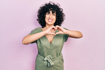 Young middle east woman wearing casual clothes smiling in love doing heart symbol shape with hands....