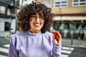 Young middle east woman smiling confident holding electronic cigarette at street