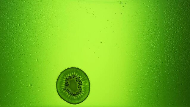 Kiwi falls into the juice. Slow motion 240 frames. Green juice. Fresh fruit