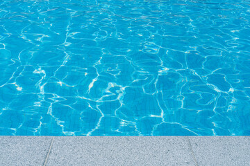 Beautiful sunny surface of swimming pool water with rippling wavy glowing blue transparent water. Abstract water surface with rippling waves background