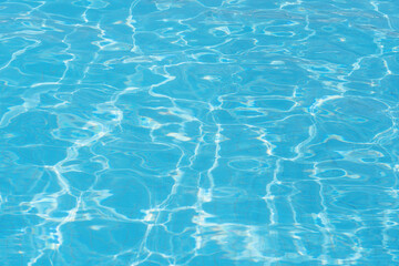 Fototapeta na wymiar Beautiful surface of swimming pool water with rippling sunny wavy glowing blue transparent water. Abstract water surface with waves background