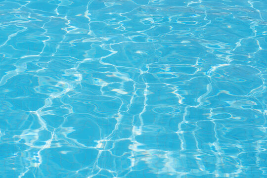 Beautiful surface of swimming pool water with rippling sunny wavy glowing blue transparent water. Abstract water surface with waves background