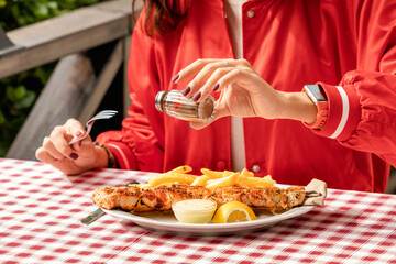 The girl adds pepper for a more spicy taste of a meat lunch in a restaurant. Excess seasonings can lead to stomach problems