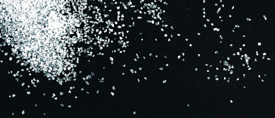 Scattered white salt on a wooden dark background. Panorama.