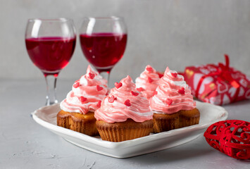 Homemade cupcakes decorated with cream and heart-shaped sprinkles for Valentine's Day on light gray background