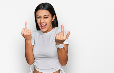 Young hispanic girl wearing casual white t shirt showing middle finger doing fuck you bad expression, provocation and rude attitude. screaming excited