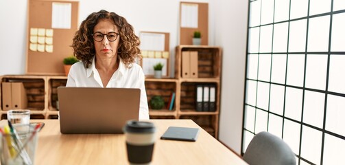 Middle age hispanic woman working at the office wearing glasses skeptic and nervous, frowning upset because of problem. negative person.