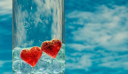 Two symbolic human hearts in a glass container with water against the background of the sky