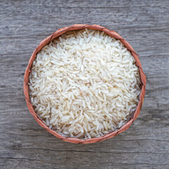 Organic raw rice in Bamboo basket on old wood desk background 