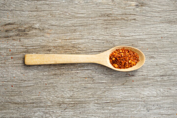 ground dried chillies in wooden spoon on wood background
