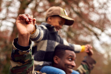 Close Up Of American Soldier Returning Home To Family On Leave Carrying Son Wearing Army Cap