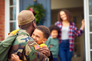 American Soldier In Uniform Returning Home To Family On Hugging Children Outside House