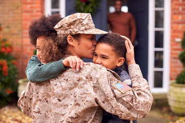 American Female Soldier In Uniform Returning Home To Family On Hugging Children Outside House - Powered by Adobe