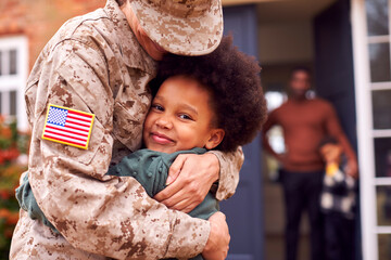 American Female Soldier In Uniform Returning Home To Family On Hugging Children Outside House