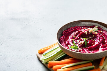 beet hummus in a ceramic bowl on a light background, copy space