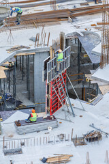 Building construction site work against blue sky.Hydraulic luffing jib tower cranes and workers...
