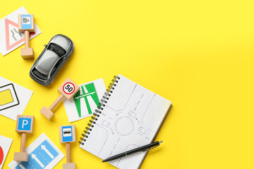 Many different road signs, notebook and toy car on yellow background, flat lay with space for text....