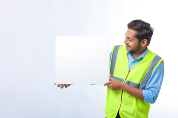 Young indian Construction Worker Showing Empty Poster Board on White Background.