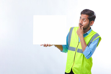 Young indian Construction Worker Showing Empty Poster Board on White Background.