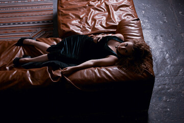 young woman lying on a leather sofa