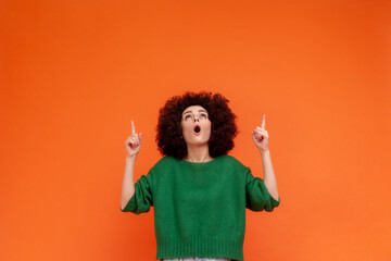 Portrait of shocked woman with Afro hairstyle wearing green casual style sweater looking and...